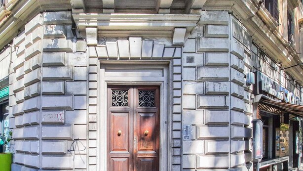 A building facade with a symmetrical entrance featuring a double wooden door with decorative metalwork. - Colosseum Cosy Apartment Close To Metro (Rome)