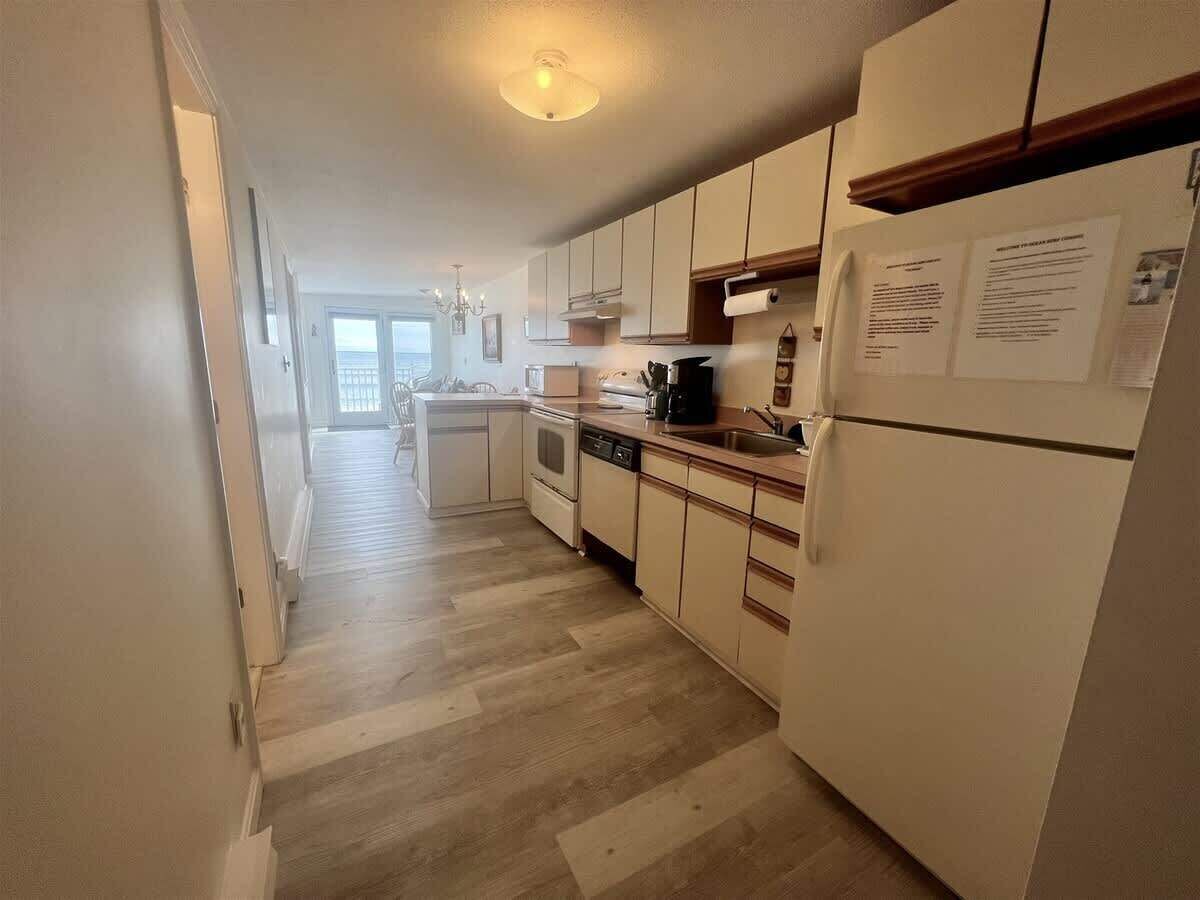 A kitchen with white cabinets, a dishwasher, and a refrigerator.