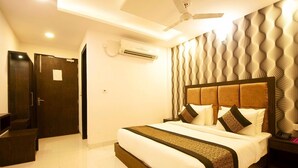 A hotel room with a large bed, a ceiling fan, an air conditioning unit, and a textured wall.