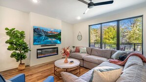 Una sala de estar moderna con chimenea, televisor grande y sofá.