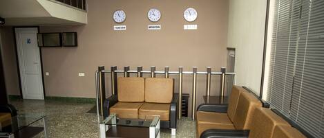 A lobby with seating, a glass coffee table, and clocks displaying different time zones.