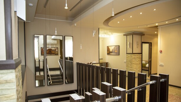 Un hall d’hôtel avec un escalier, un comptoir d’accueil et un grand miroir qui reflète l’intérieur.