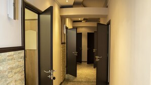 Un couloir d’hôtel avec de nombreuses portes, un sol à motifs et un éclairage encastré au plafond.