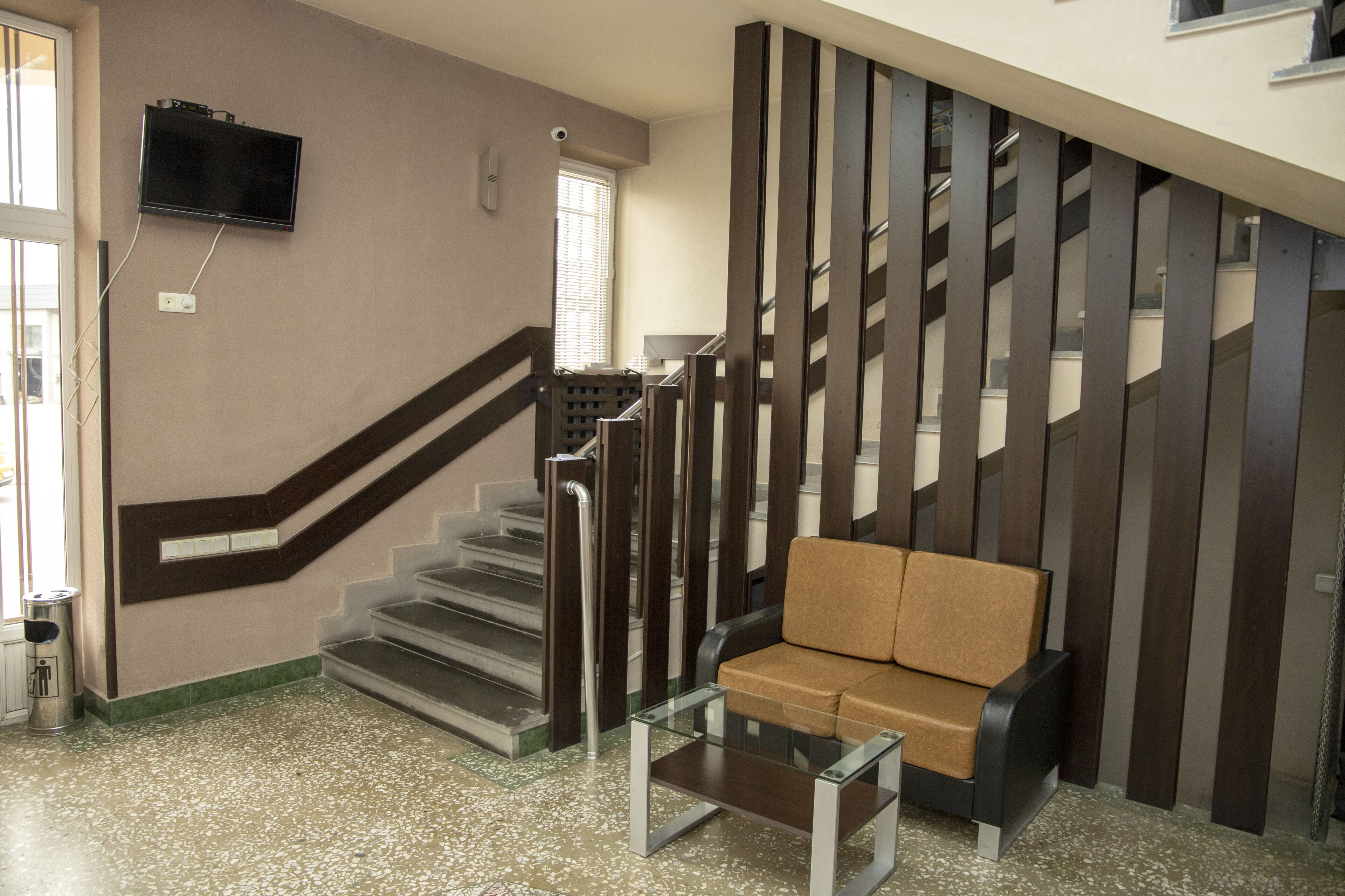 A modern interior with a staircase, a sofa, and a TV mounted on the wall.