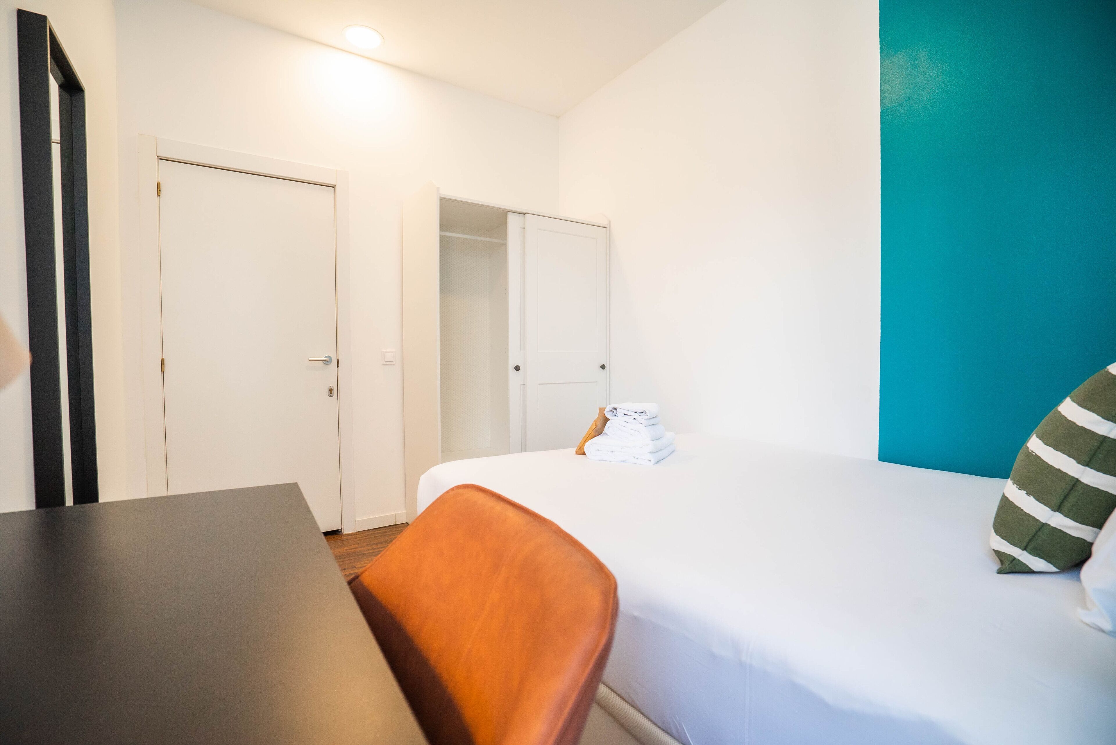 Une chambre d’hôtel avec un lit, une table et deux portes.