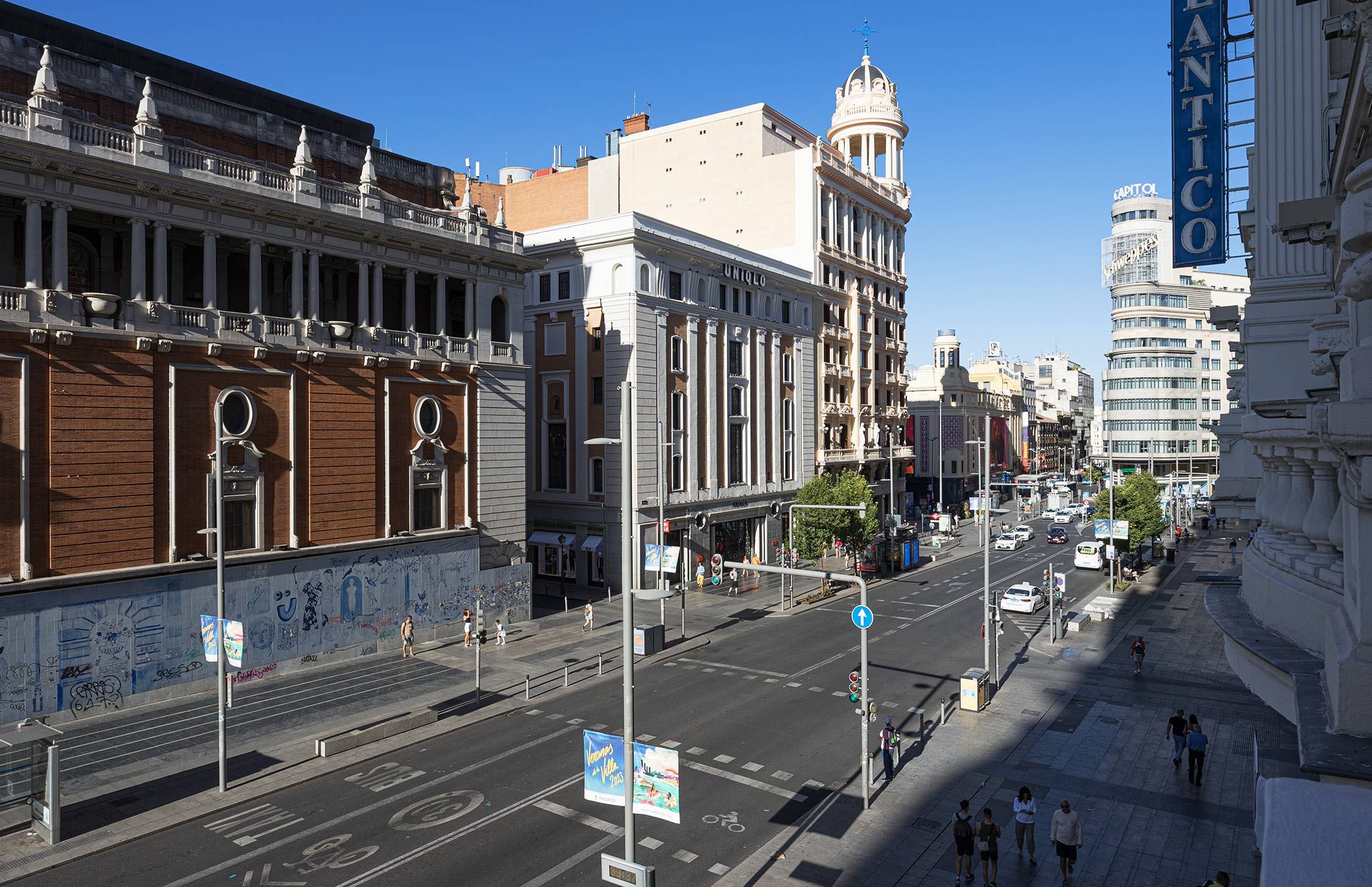 Eine Stadtstraße mit historischen Gebäuden, blauem Himmel und Fußgängern.
