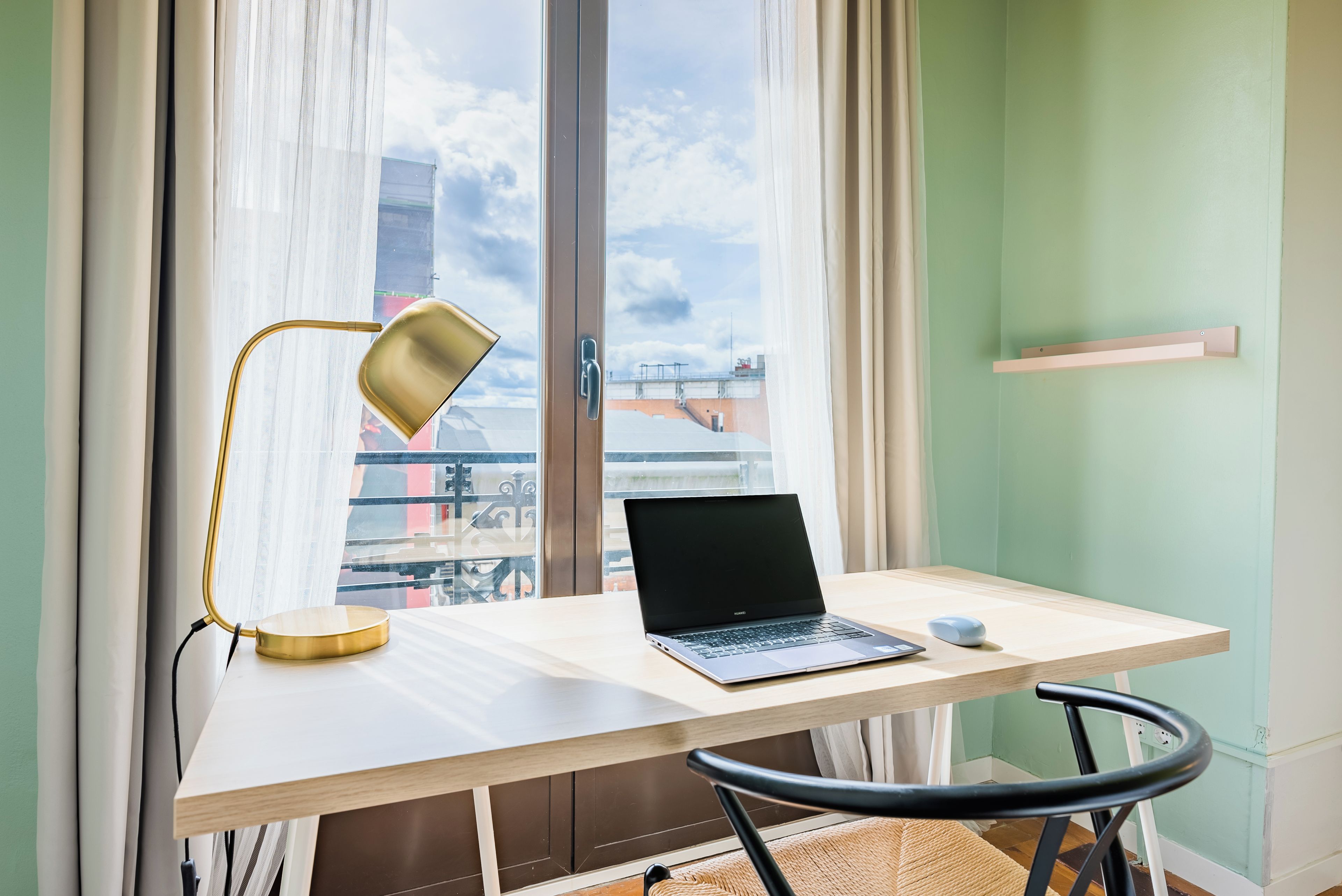 A workspace with a laptop, a desk lamp, and a chair.