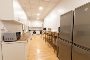 A modern kitchen with stainless steel appliances, wooden flooring, and white cabinetry. - Live It Gran Via (Madrid)