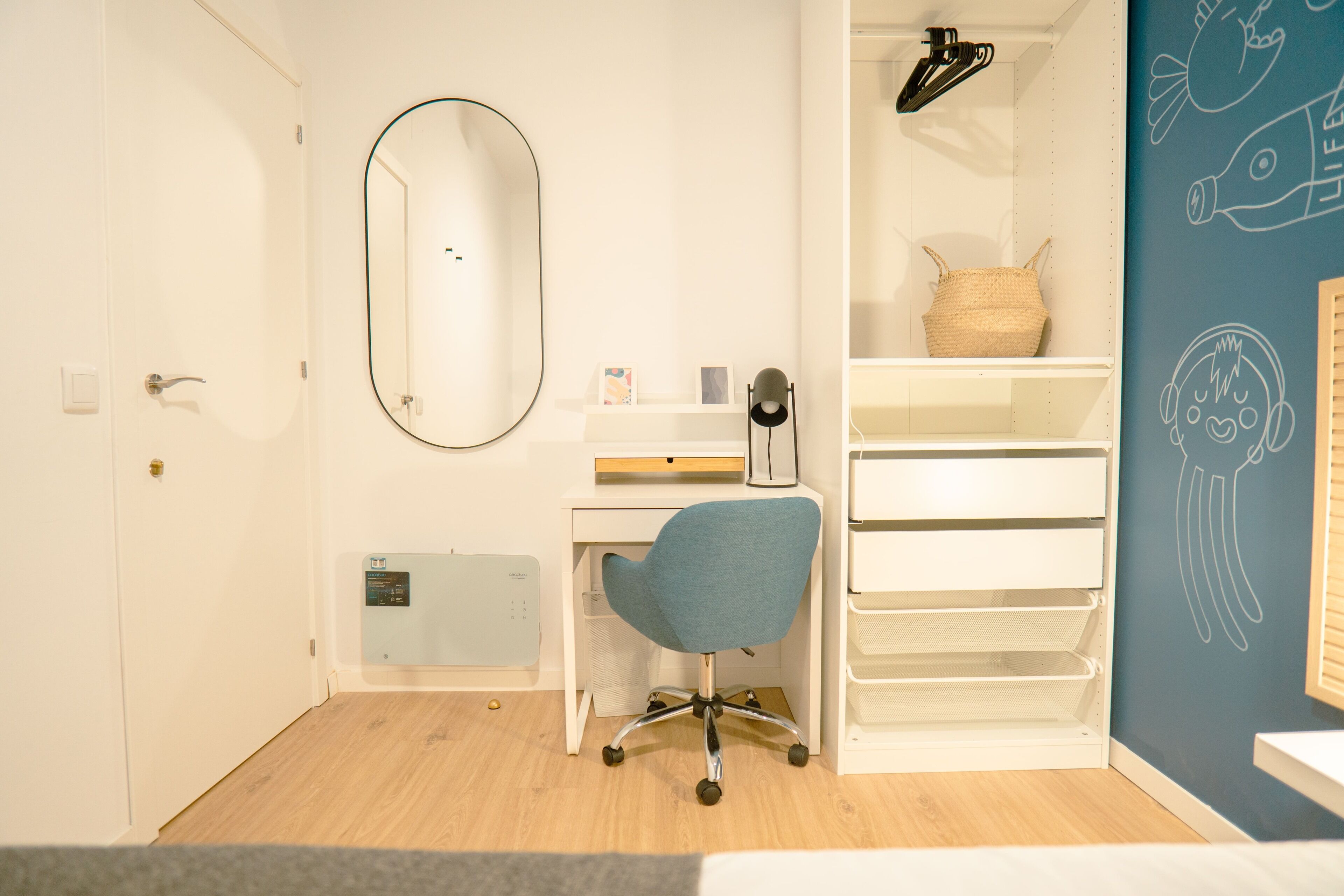 Een kamer met een bureau, stoel, planken en een spiegel.