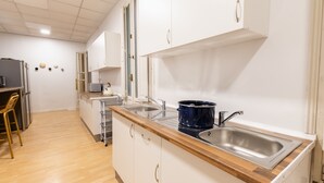 A modern kitchen with white cabinets, a wooden countertop, a sink, and a stove. - Live It Gran Via (Madrid)