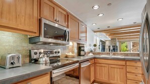 Une cuisine moderne avec des meubles en bois, des appareils électroménagers en acier inoxydable et un pare-feu en pierre.