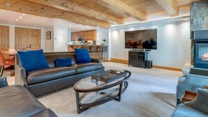 Un salon spacieux avec un canapé en cuir, une table basse en verre et une cheminée.