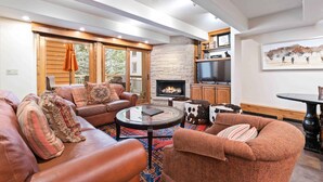 A spacious living room with leather sofas, a glass coffee table, a fireplace, and a television. - Lodge at Lionshead 203 (Vail)