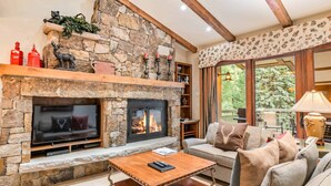 A cozy living room with a stone fireplace, a flat-screen TV, and a comfortable sofa. - Lodge at Lionshead 404 (Vail)