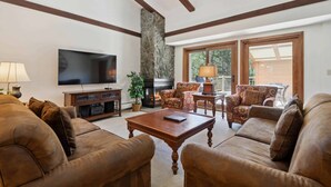 Ein Wohnzimmer mit Kamin, Ledersofas, einem Fernseher und einer Steinsäule.