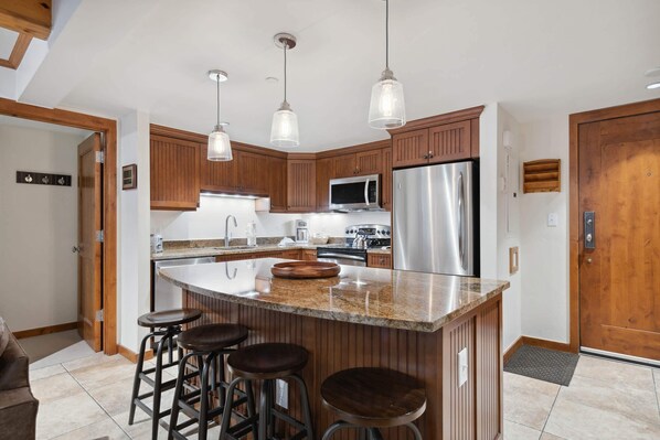 A modern kitchen with wooden cabinets, stainless steel appliances, and a central island with stools.