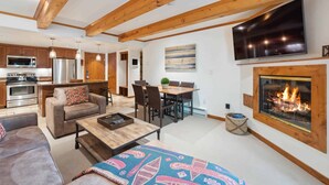 A modern living room with a fireplace, a dining area, and a kitchen. - Lodge at Lionshead 120B (Vail)