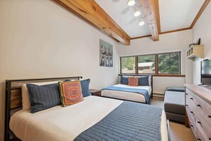 Un dormitorio con dos camas, un aparador de madera y una televisión.