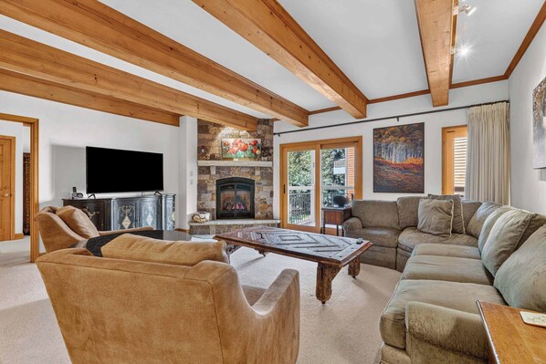 A spacious living room with a fireplace, a television, and a large sofa.