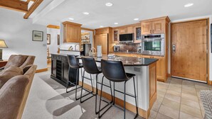 A modern kitchen with wooden cabinets, a central island with bar stools, and a large oven.