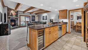 A spacious kitchen with wooden cabinets, a large island, and a stone fireplace.