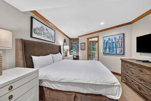 A hotel room with a large bed, a dresser, a television, and artwork on the walls. - Lodge at Lionshead 210 (Vail)