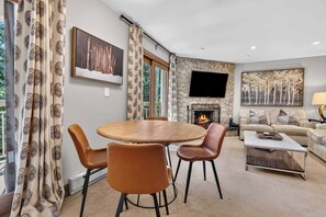 Un salon chaleureux avec une cheminée, une table à manger ronde et des sièges confortables.