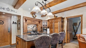 A kitchen with wooden cabinets, a marble island, and patterned chairs. - Lodge at Lionshead 230 (Vail)