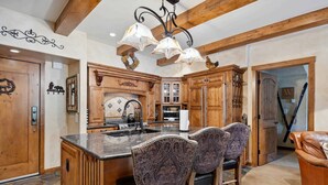 A kitchen with wooden cabinets, a marble island, and patterned chairs. - Lodge at Lionshead 230B (Vail)