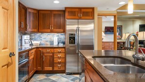 Une cuisine moderne avec des meubles en bois, des appareils en acier inoxydable et un plan de travail en granit.