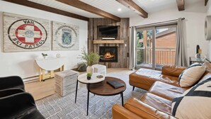 A modern living room with a fireplace, leather sofa, and artwork on the wall. - Lodge at Lionshead 260A (Vail)