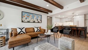 A modern living room with a brown leather sofa, a round coffee table, and a patterned rug. - Lodge at Lionshead 260A (Vail)
