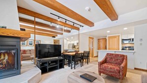 A modern living room with a fireplace, a TV, and a dining area with chairs and a table. - Lodge at Lionshead 270B (Vail)