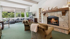 A cozy living room with a stone fireplace, comfortable seating, and a television. - Lodge at Lionshead 01 (Vail)