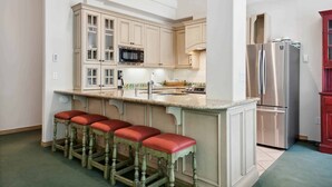 A kitchen with a central island, bar stools, stainless steel appliances, and light-colored cabinetry. - Lodge at Lionshead 01 (Vail)