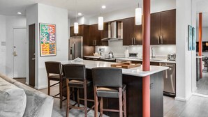Una cocina moderna con armarios de madera oscura, electrodomésticos de acero inoxidable y una isla central con taburetes de bar.