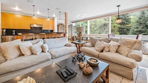 A modern living room with a sofa, coffee table, and a dining area with a table and chairs.