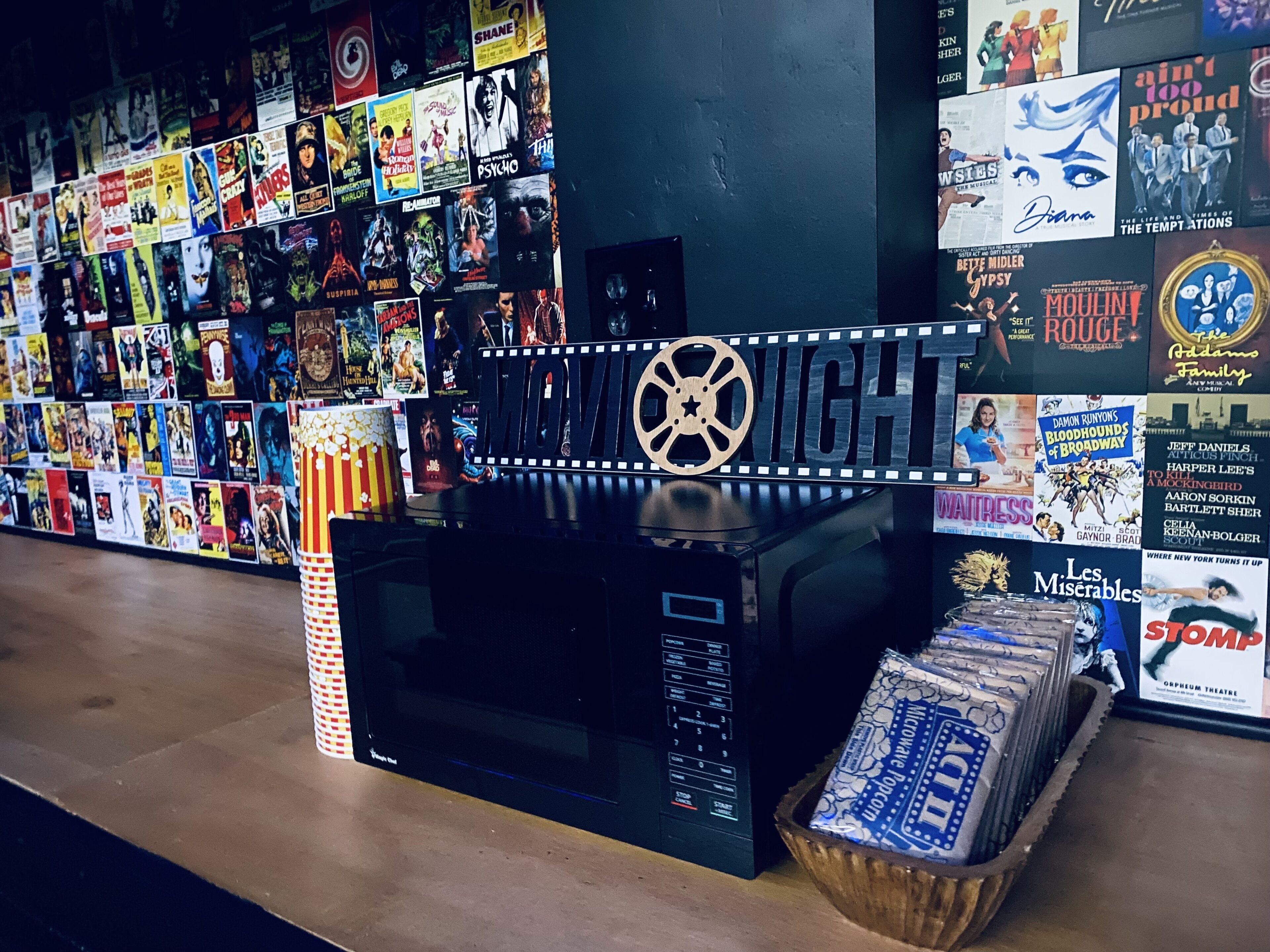 A movie-themed display with a microwave, popcorn, and various movie posters.