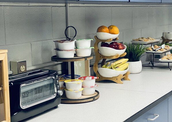 A kitchen counter with a toaster, a fruit bowl, and a tray of pastries.