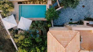 An aerial view of a property with a swimming pool, outdoor seating, and a stone wall. - Riglia Villas - Villa Olive (West Mani)
