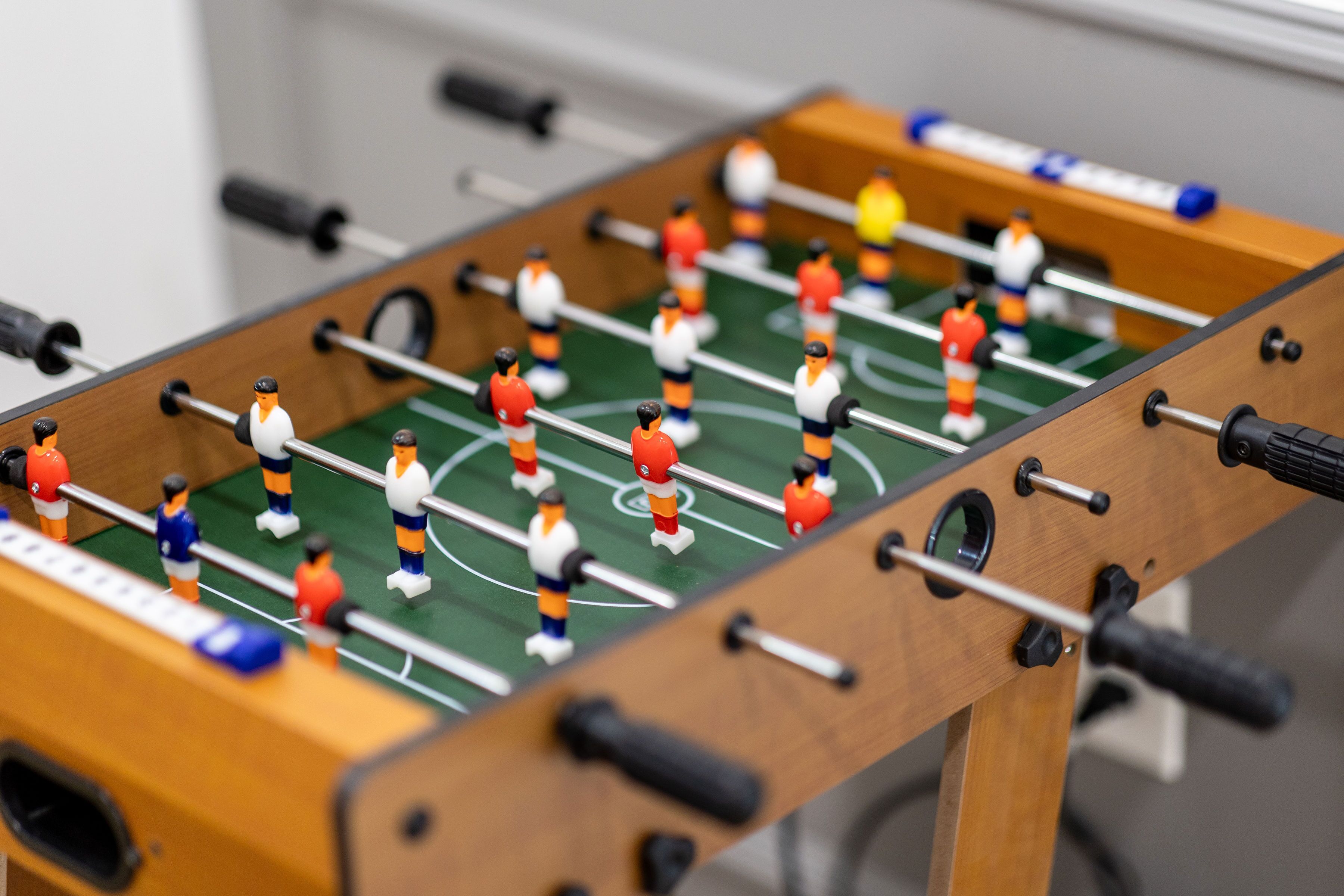A close-up of a foosball table with players in red, white, and blue uniforms.
