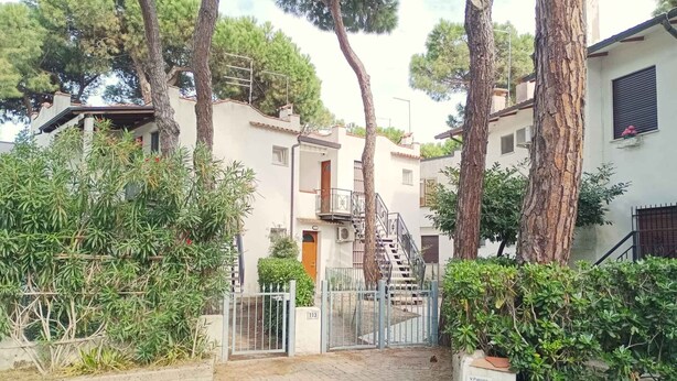 A residential area with a gated entrance, a staircase leading to a second-floor apartment, and surrounding greenery. - Holiday home with air conditioning and washing machine (Rosolina Mare)