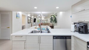 A modern kitchen with a central island, stainless steel appliances, and a built-in dishwasher.