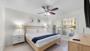A bedroom with a bed, bedside tables, a ceiling fan, and a window with blinds.