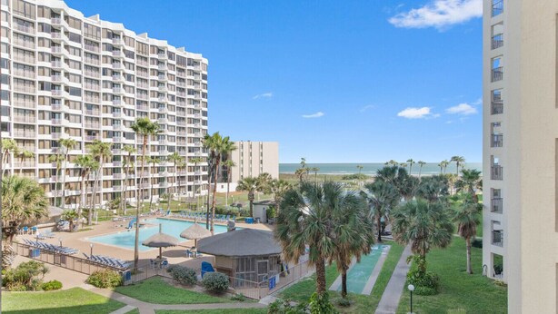 Un hotel con piscina, palmeras y vista al océano.