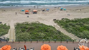 A beach with umbrellas, a pathway, and a view of the ocean. - Luxury Beachfront Condo With Amazing Sunset Views (South Padre Island)