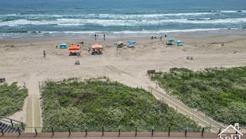 A beach with umbrellas, a pathway, and a view of the ocean.