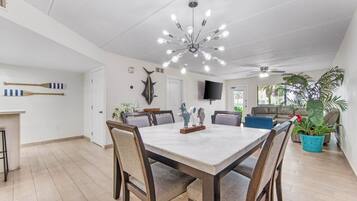 Un comedor espacioso con una mesa de mármol, sillas de madera y una lámpara moderna.