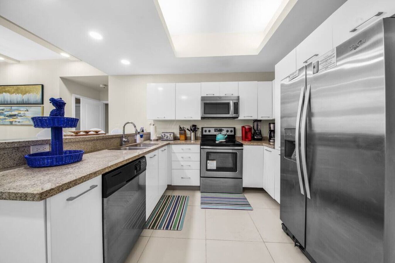 A modern kitchen with white cabinets, stainless steel appliances, and a blue decorative fountain.