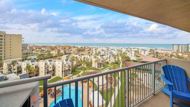 Ein Balkon mit Blick auf ein Resort, darunter ein Pool und Palmen.